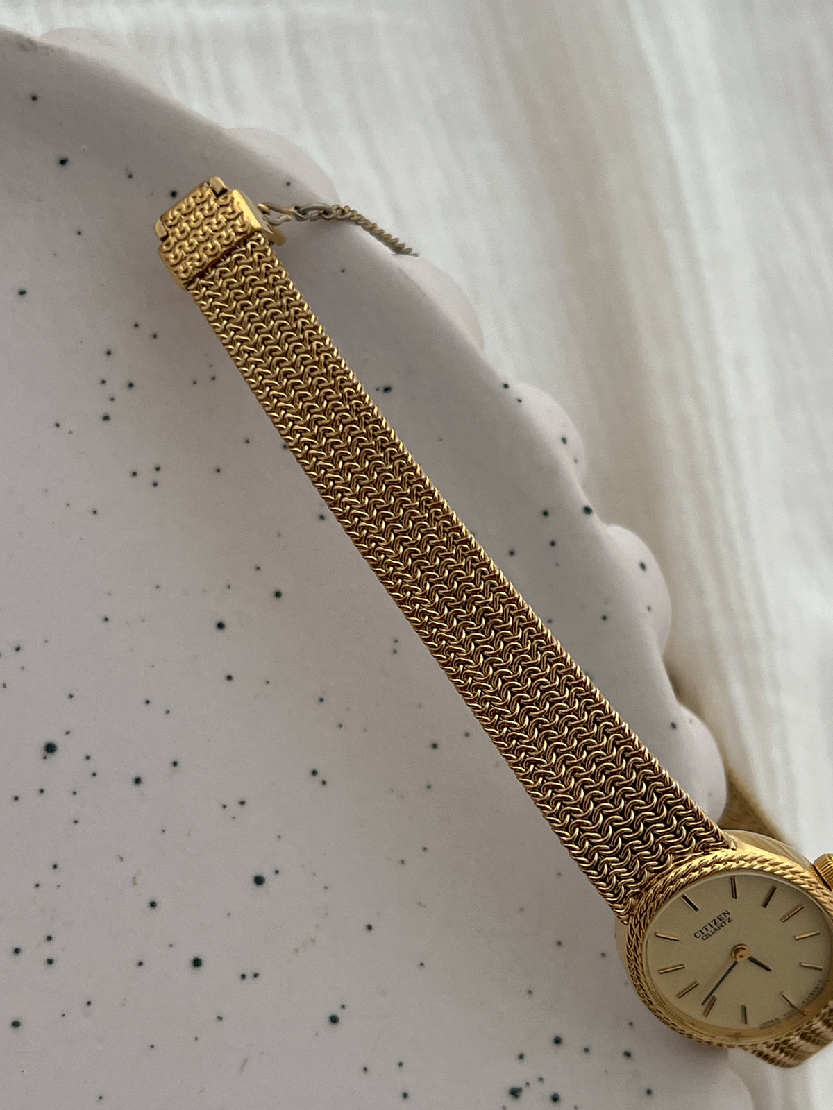 Angled view of the Citizen oval watch's rope bezel and gold-tone mesh bracelet.