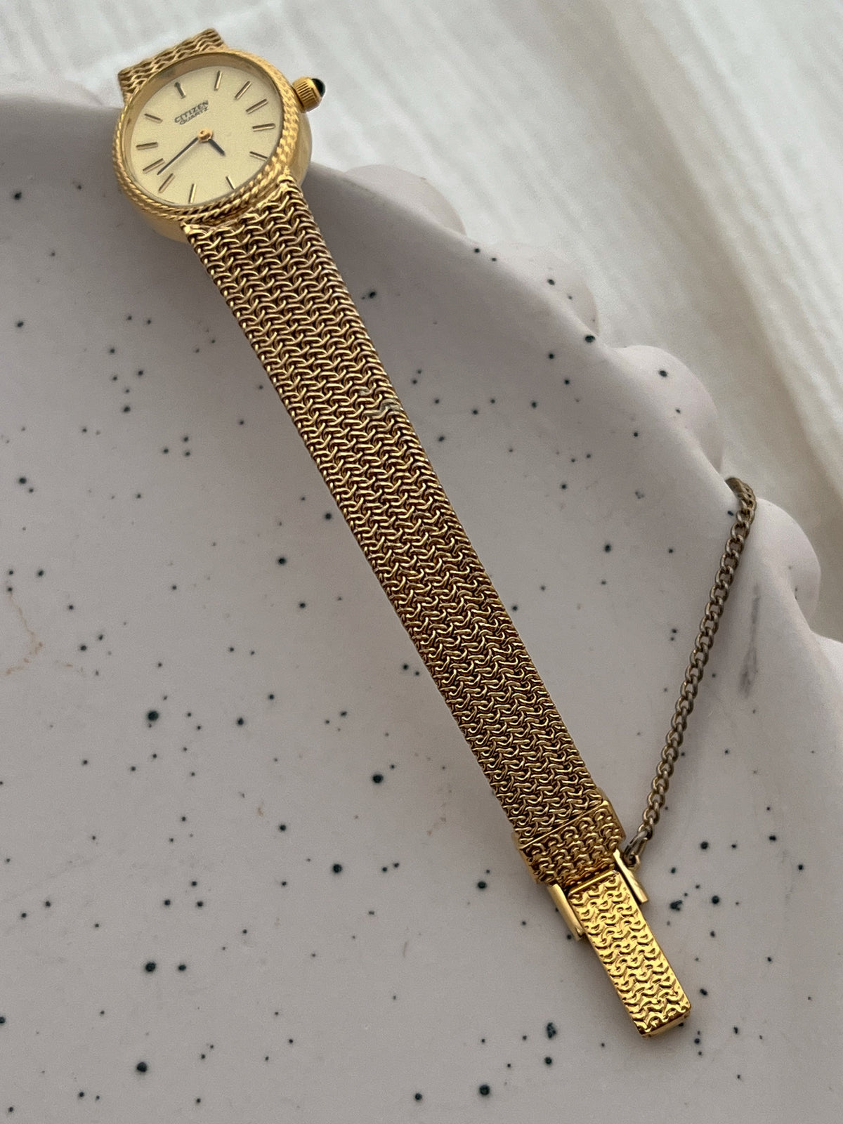 Wrist view of the Citizen ladies watch with its woven gold-tone chain mesh bracelet.