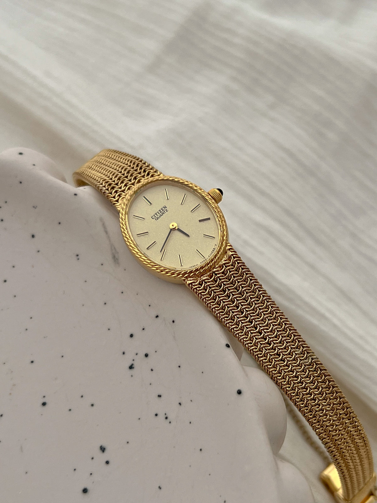 Detail of the Citizen watch's woven gold-tone chain mesh bracelet.