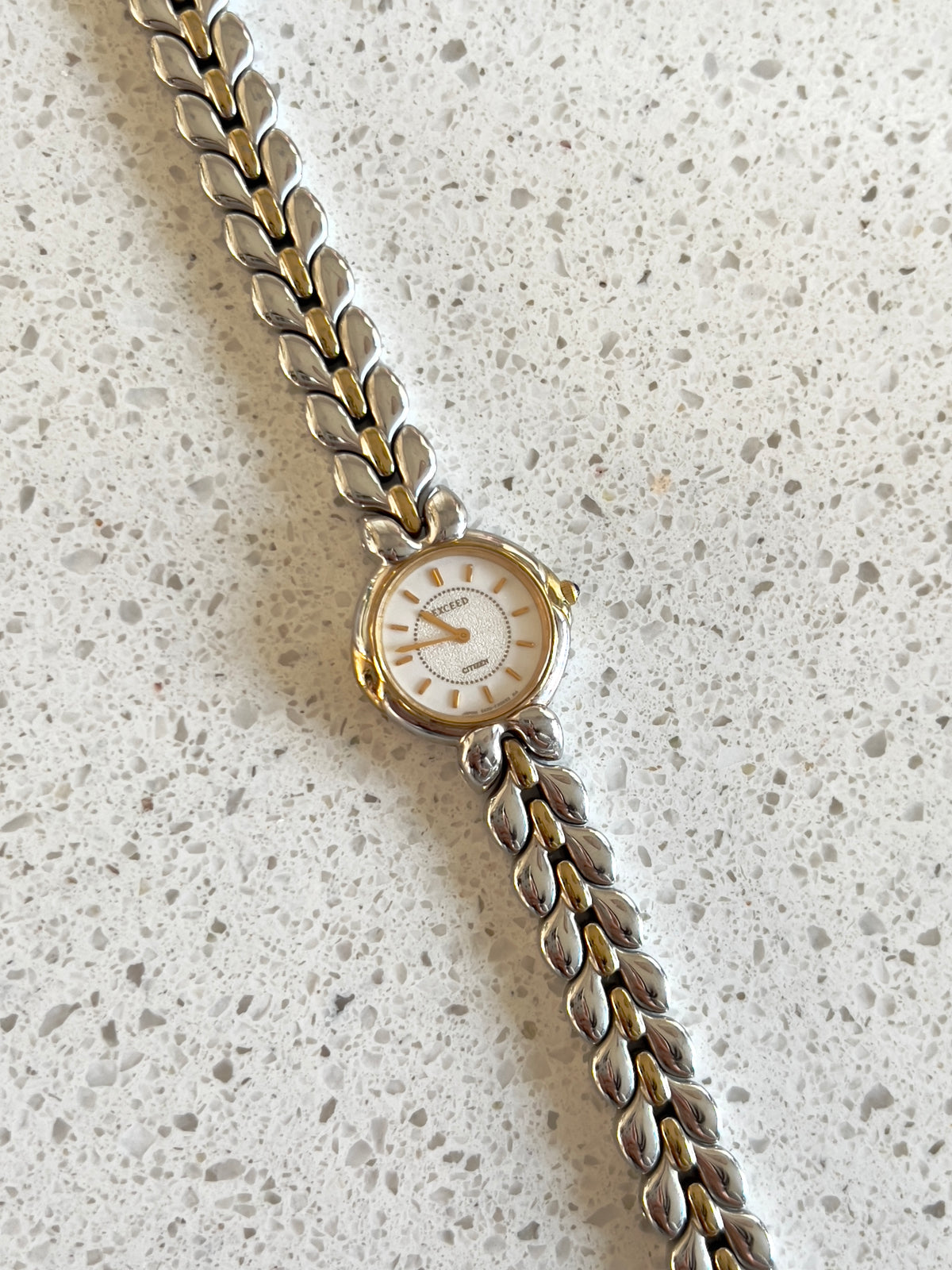 Citizen Two Tone Woman's Watch with Leaf Bracelet, Diamond Dust Dial & Blue Crown Stone — side view of the case and crown.