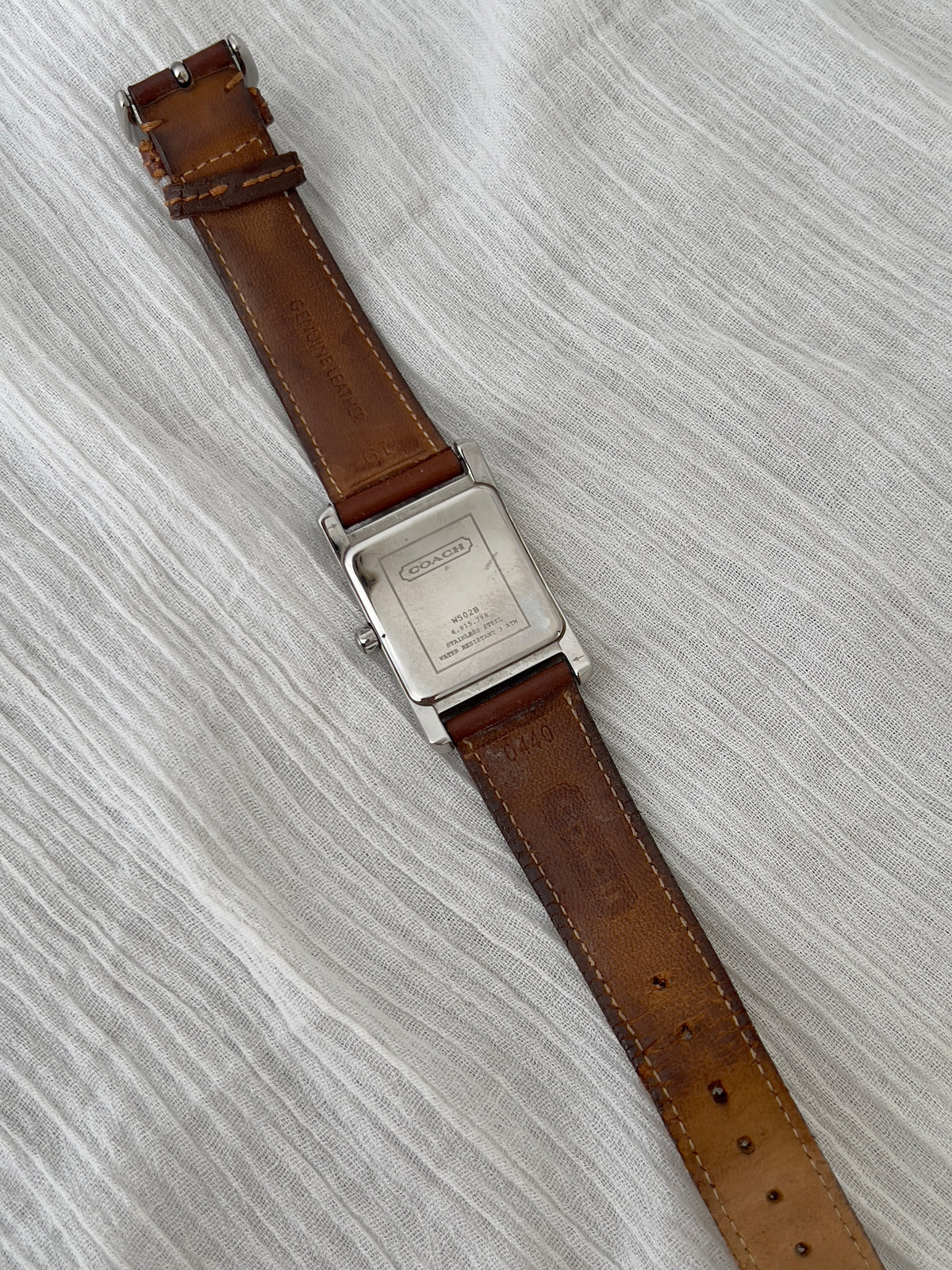 Front view of the Coach rectangular watch with silver dial and date.