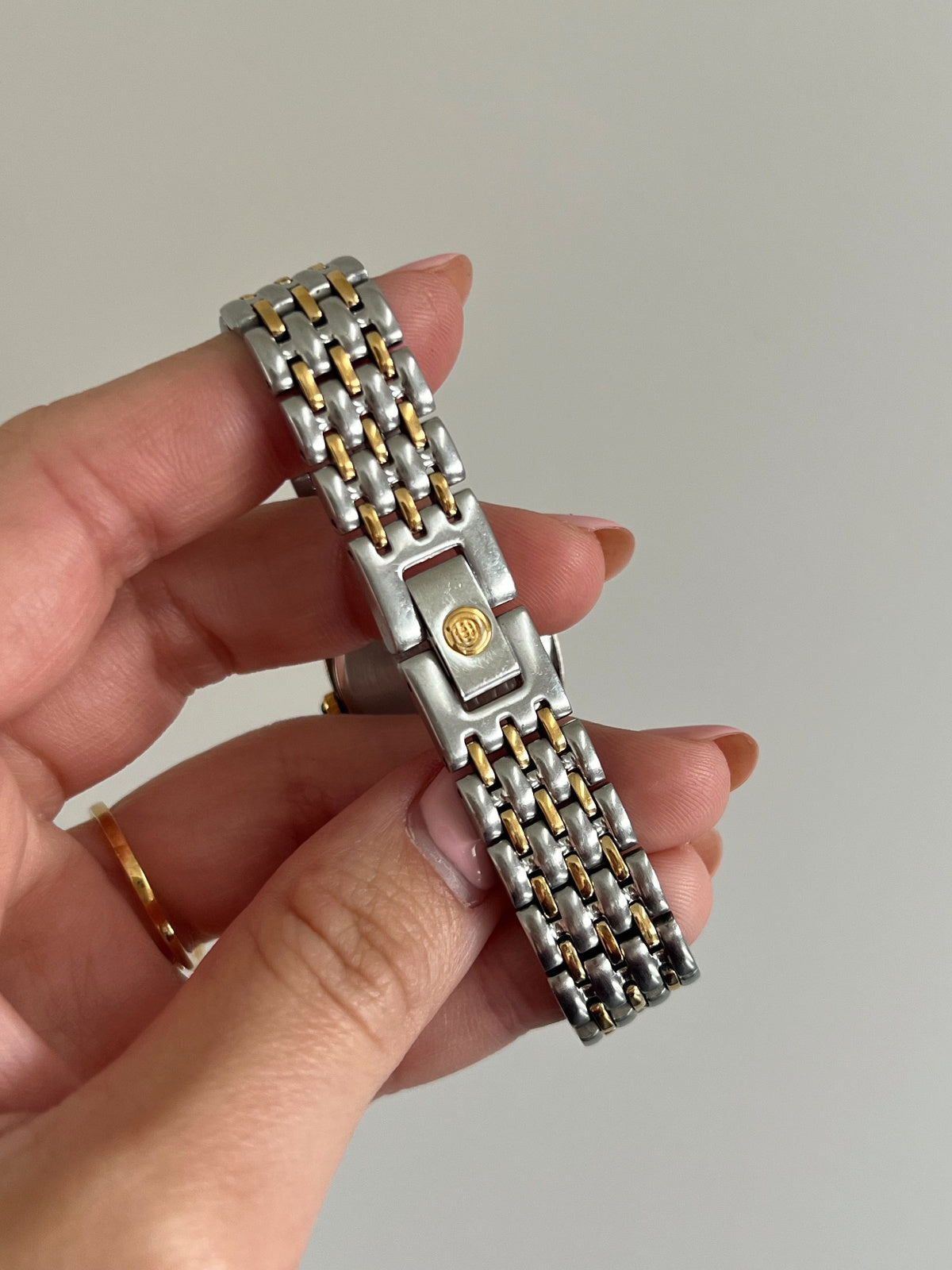 Cyma emblem on the folding jewellery clasp of the silver and gold tone link bracelet.