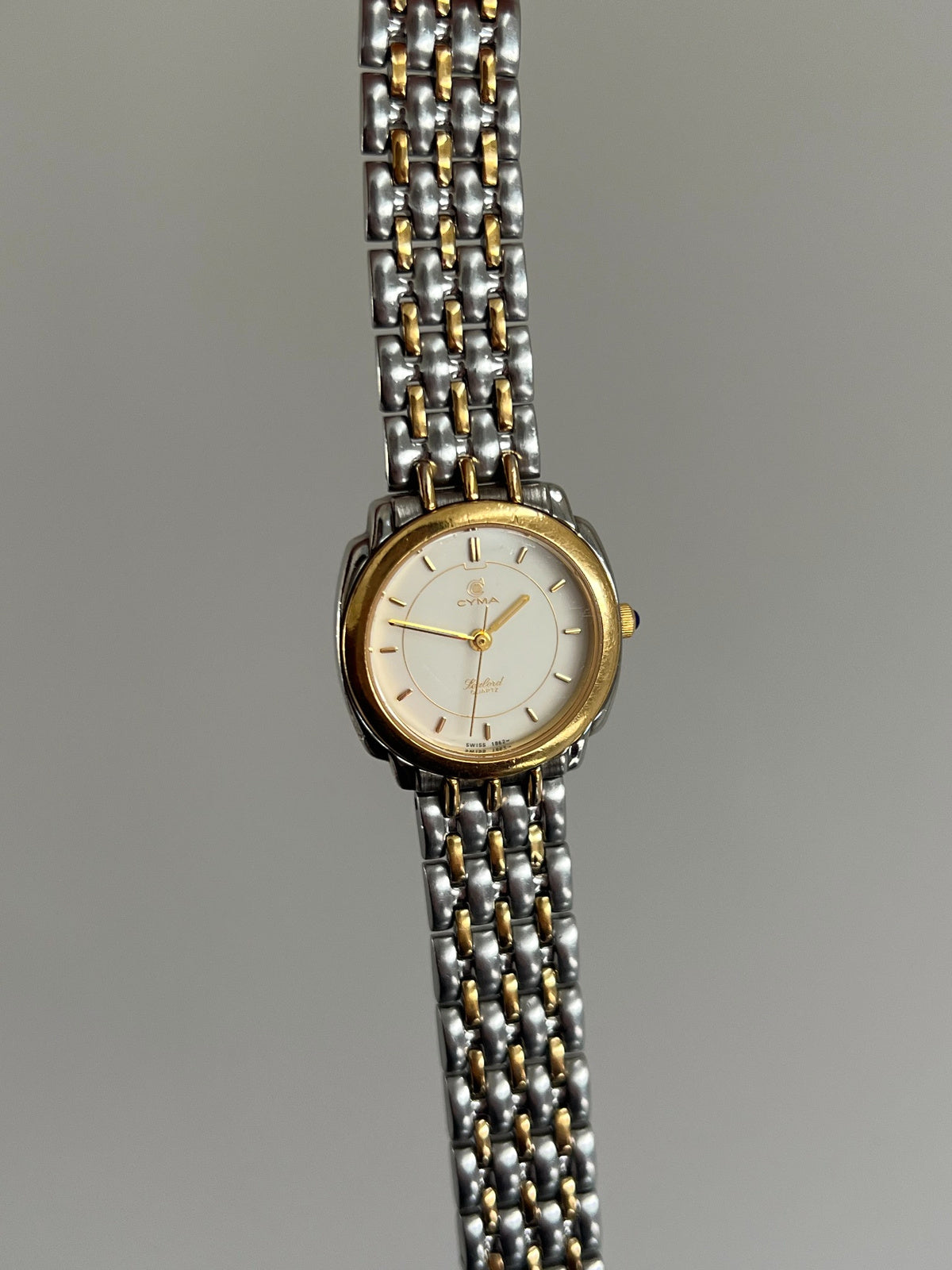 Upright front view of the Cyma Sealord cream dial, gold tone inner circle and full two tone bracelet.