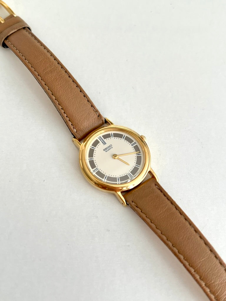 Close view of the Seiko ivory dial with grey outer panels, pale Roman markers and two gold tone hands