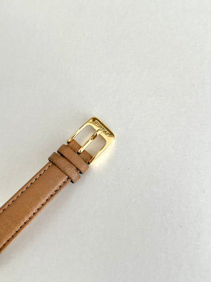 Close view of the Seiko signed gold tone pin buckle and tan leather strap keepers