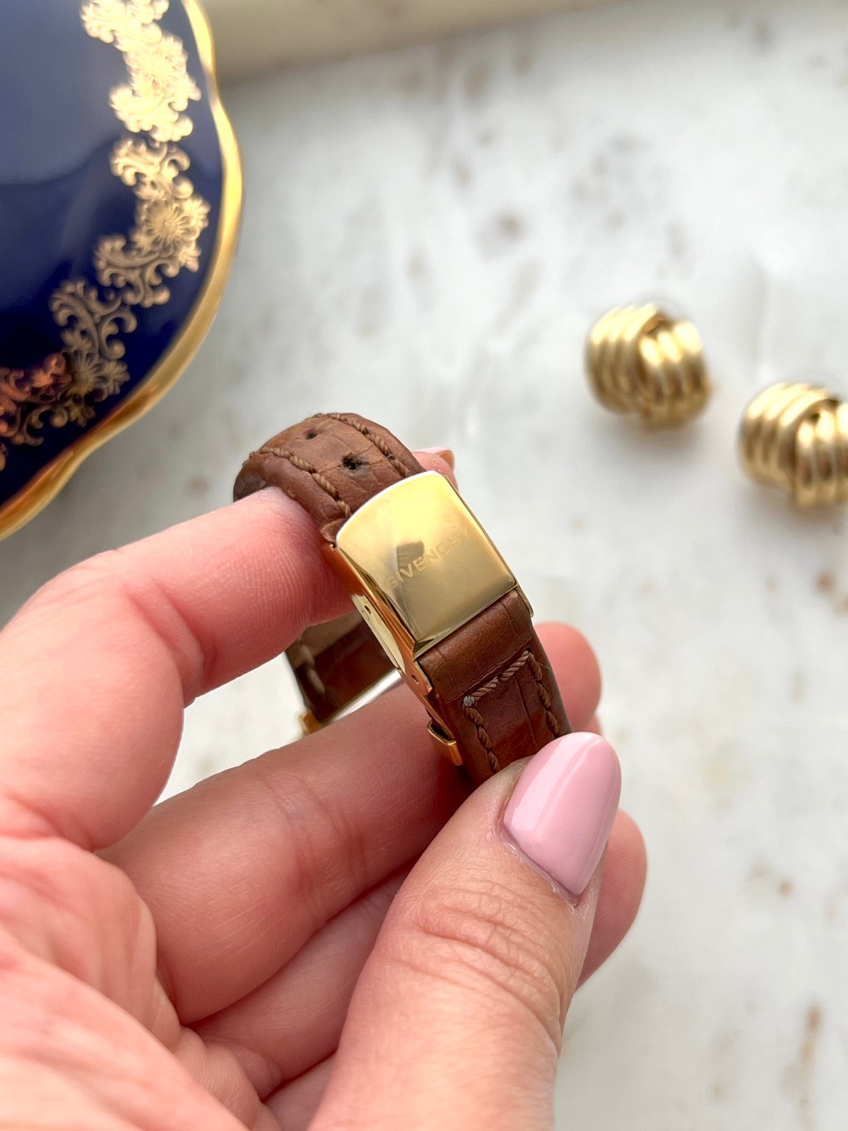 Givenchy signed gold tone folding clasp on the brown patterned leather strap