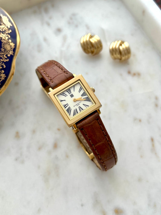 Givenchy rectangular gold tone watch with brown patterned leather strap in a marble still life