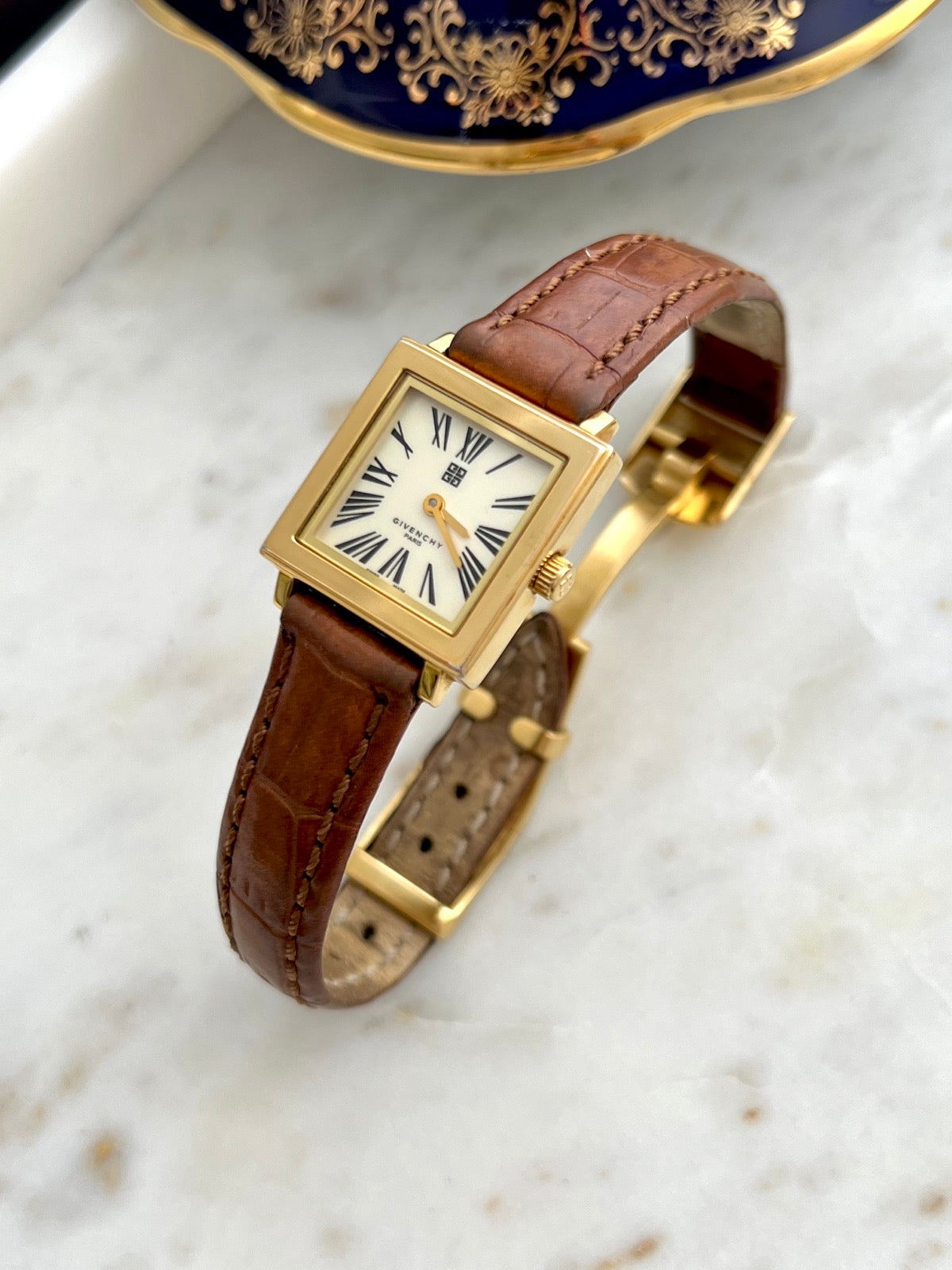 Angled front view of the Givenchy cream Roman dial watch and brown stitched leather strap