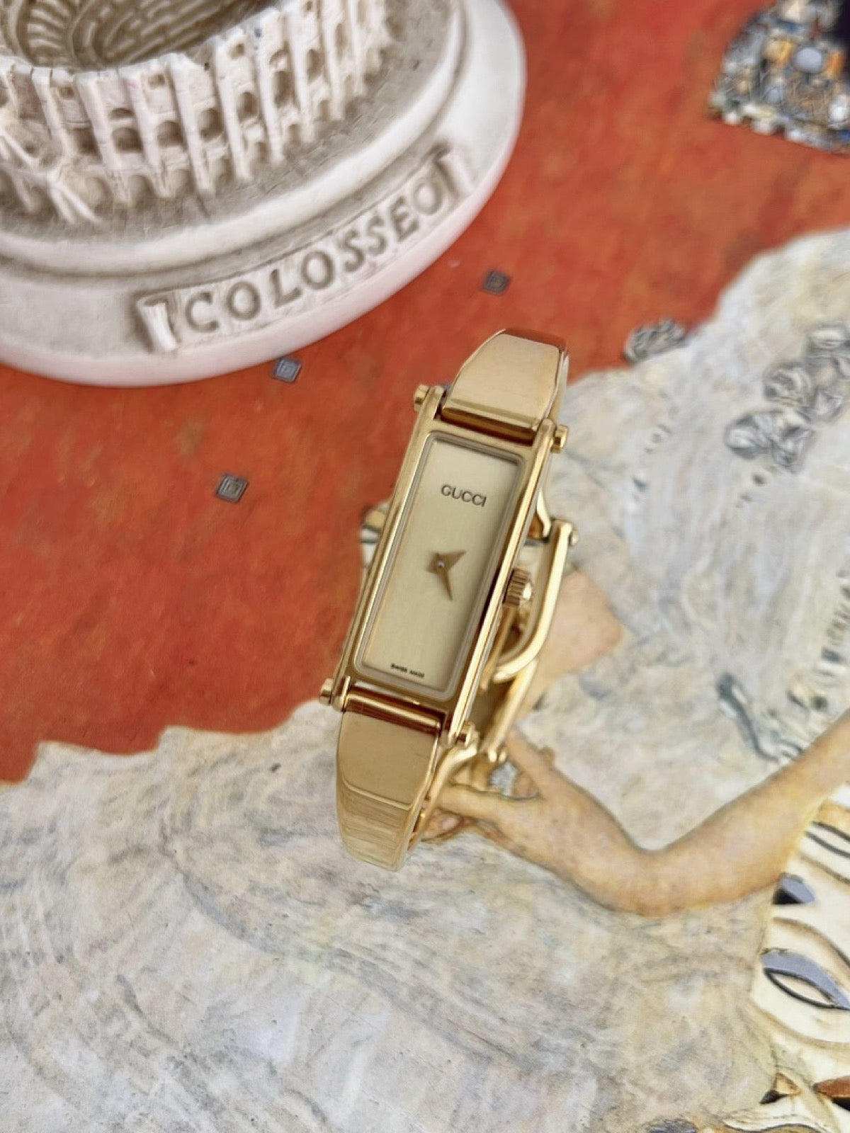 Left angled view of the Gucci women’s champagne dial watch and polished gold tone horsebit bangle