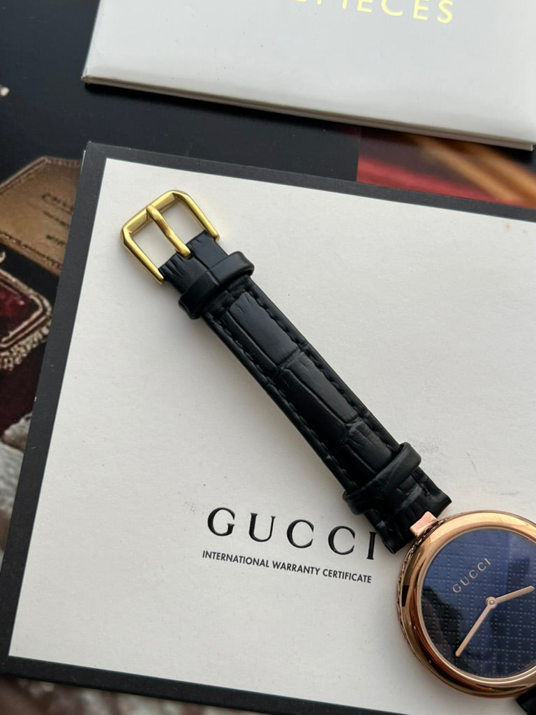 Black embossed leather strap, keepers and gold tone pin buckle on the Gucci Diamantissima women’s watch.