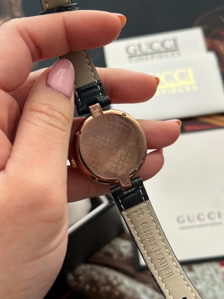 Gucci Diamantissima watch showing its engraved stainless steel case back and the genuine leather marking on its strap underside.