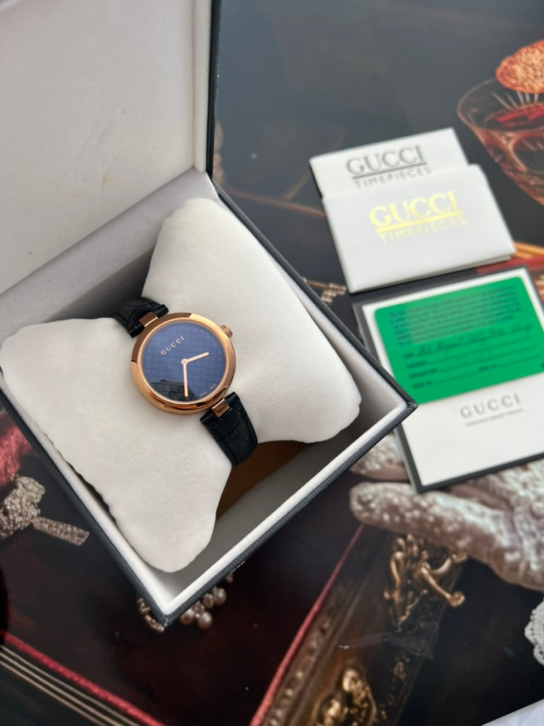 Gucci Diamantissima women’s watch with a rose gold tone case, dark Diamante patterned dial and black leather strap in a presentation box.
