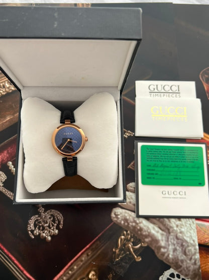 Gucci Diamantissima watch in its open presentation box beside photographed Gucci timepiece booklets and paperwork.