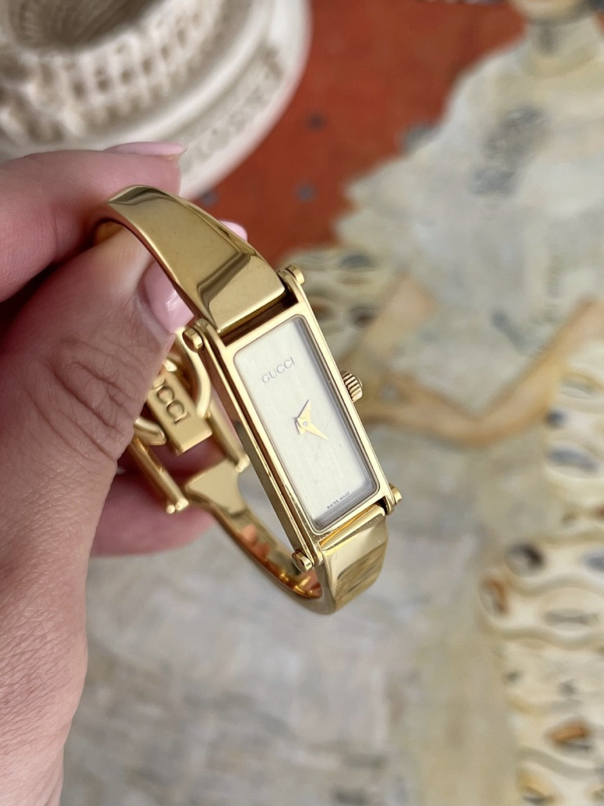 Close view of the Gucci women’s champagne dial, sculptural gold tone hands and polished gold tone rectangular case