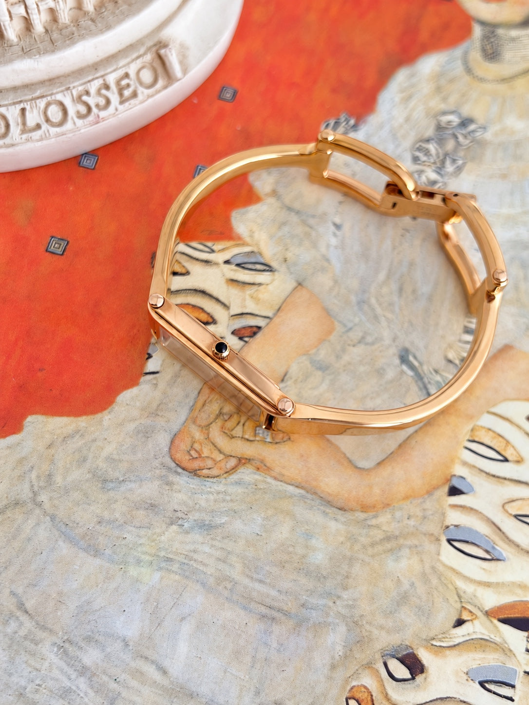 Side profile of the Gucci women’s rose gold tone bangle watch showing the slim rectangular case, black cabochon crown and curved bangle