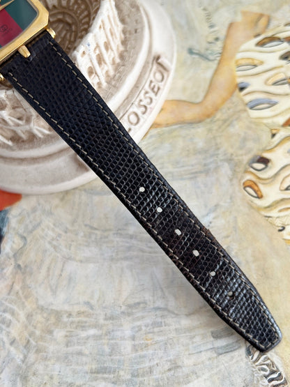 Black textured leather strap and adjustment holes on the Gucci Sherry gold tone women’s watch.