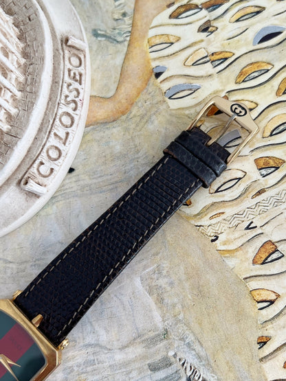 Gucci Sherry women’s watch with a black textured leather strap and gold tone pin buckle bearing the GG emblem.