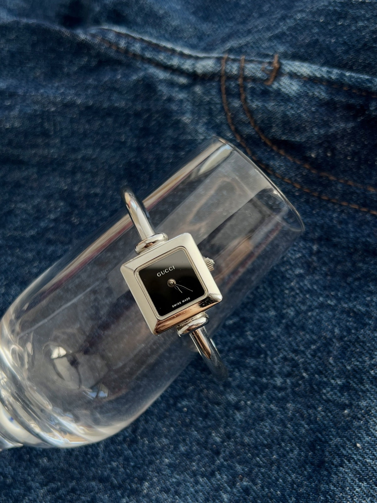 Close view of the Gucci women’s black square dial watch with polished steel case and slim bangle