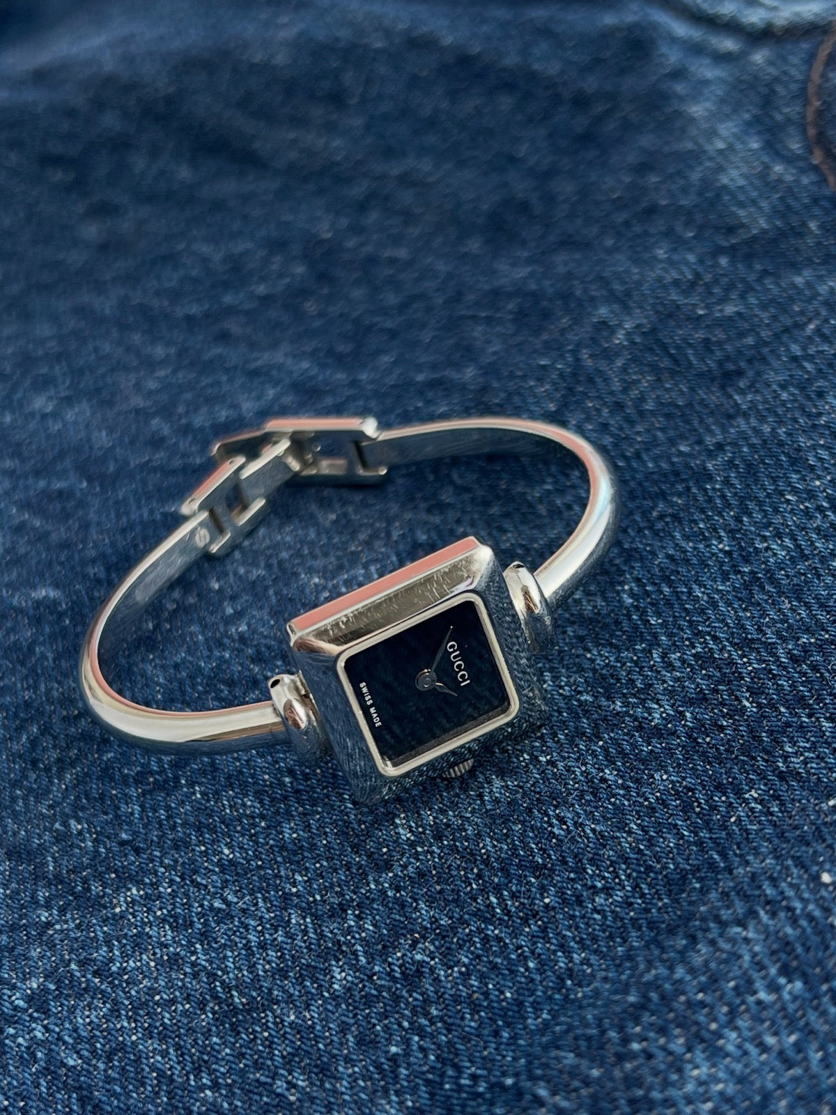 Side view of the Gucci women’s square steel watch showing the curved bangle and clasp