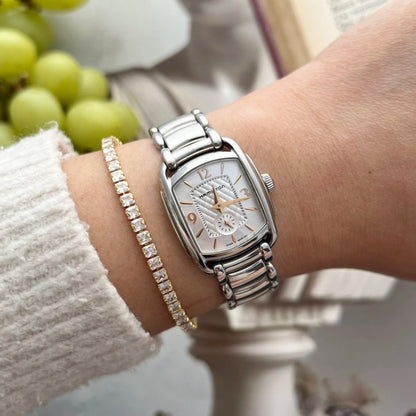 Hamilton Bagley watch with a silver quilted dial, rose gold tone numerals and polished steel bracelet, worn on a 15 cm wrist beside a fine tennis bracelet.
