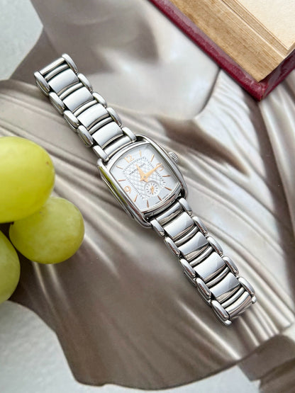 Hamilton American Classic Bagley watch with a silver quilted dial, rose gold tone hands and polished steel bracelet beside grapes and an open book.