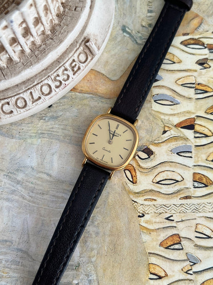 Close view of the Longines champagne dial, dark baton markers, two hands and softly squared gold tone case