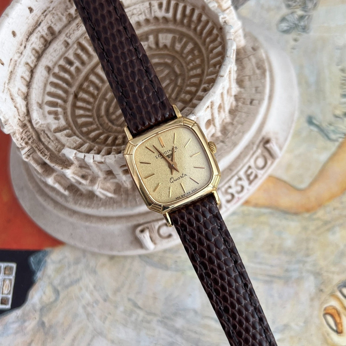 Longines champagne dial women’s watch shown at an angle on a sculptural Colosseum model.