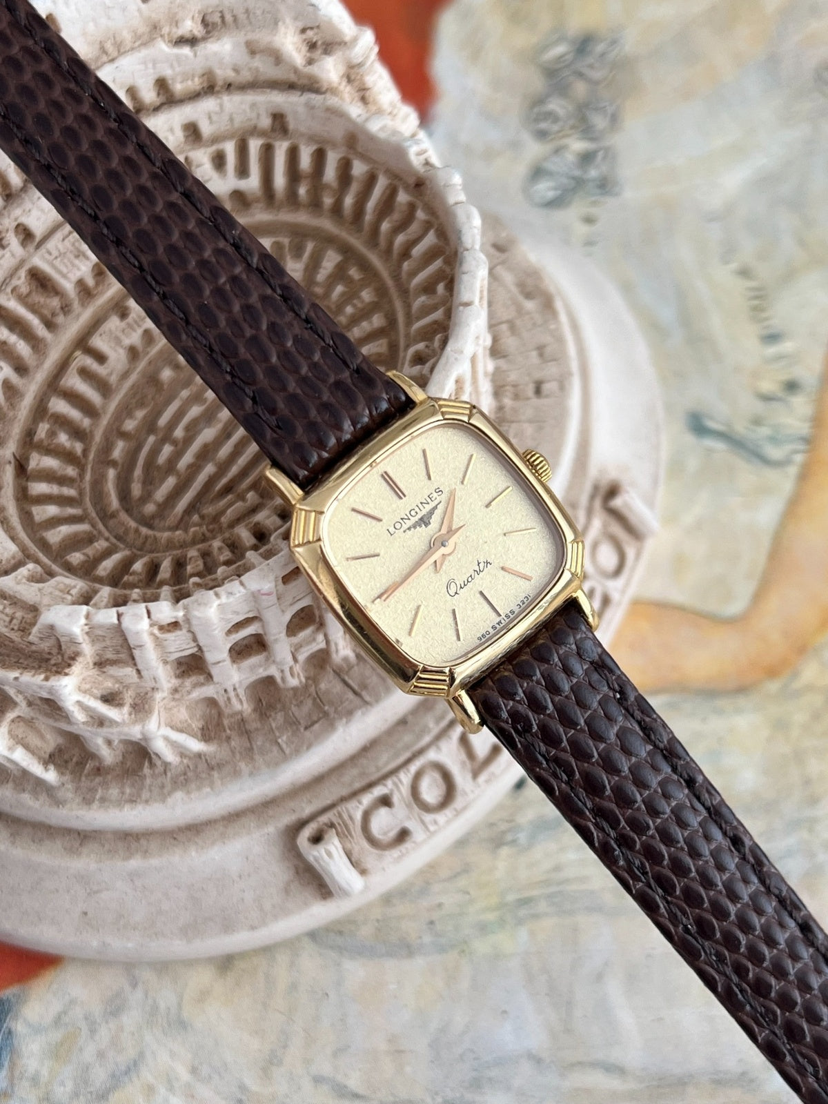 Close view of the textured champagne dial, doubled twelve marker and gold tone pointed hands.
