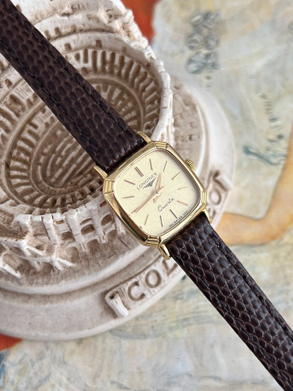 Close view of the textured champagne dial, doubled twelve marker and gold tone pointed hands.