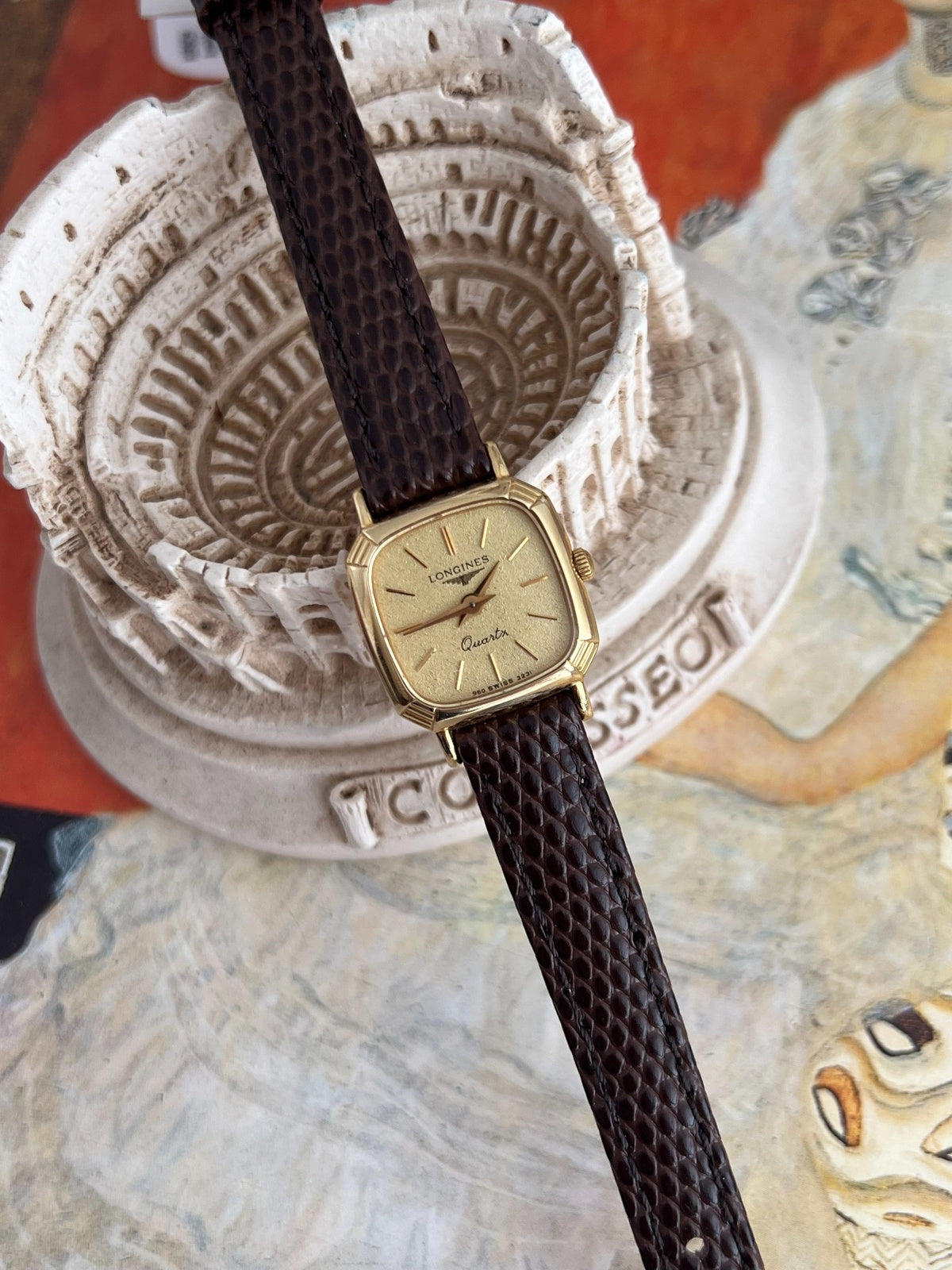 Angled view of the Longines cushion case showing polished gold tone sides and fine corner grooves.