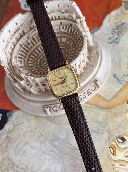 Angled view of the Longines cushion case showing polished gold tone sides and fine corner grooves.