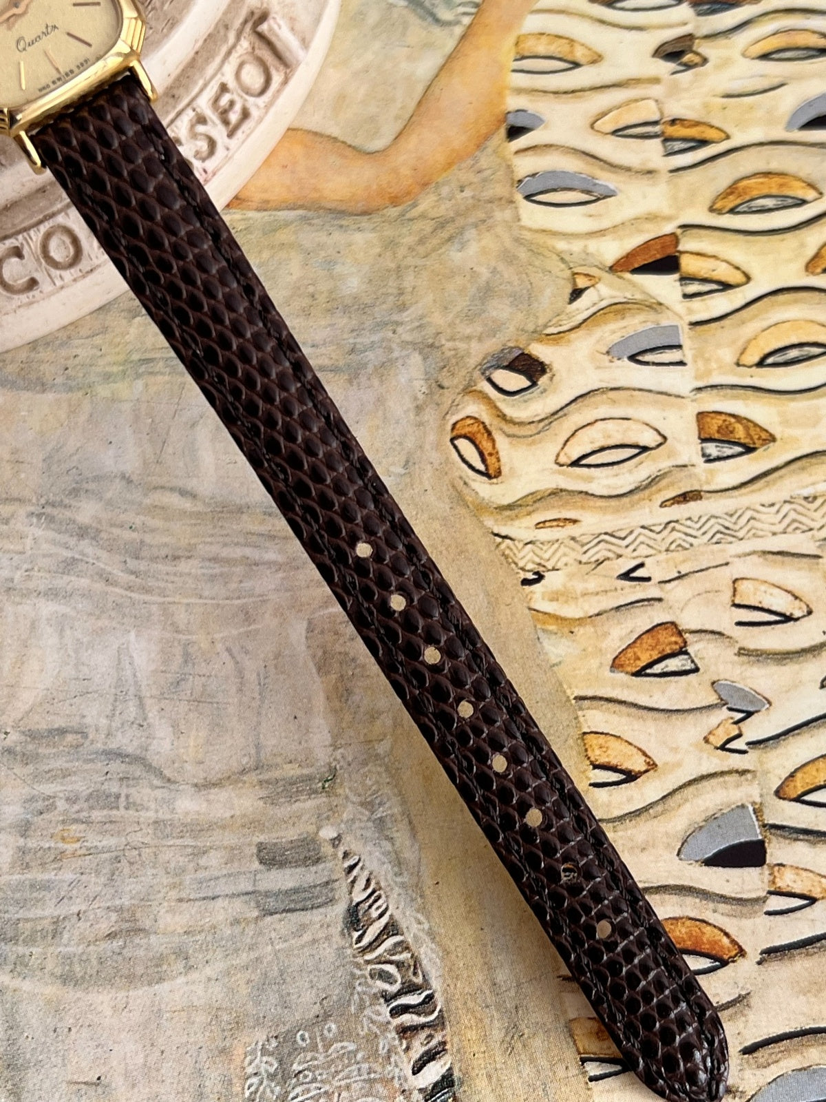 Brown Hirsch leather strap showing raised scale pattern, stitching and adjustment holes.