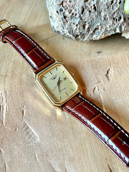 Longines Champagne Textured Bezel Women’s Watch — Full watch laid diagonally on a wooden surface