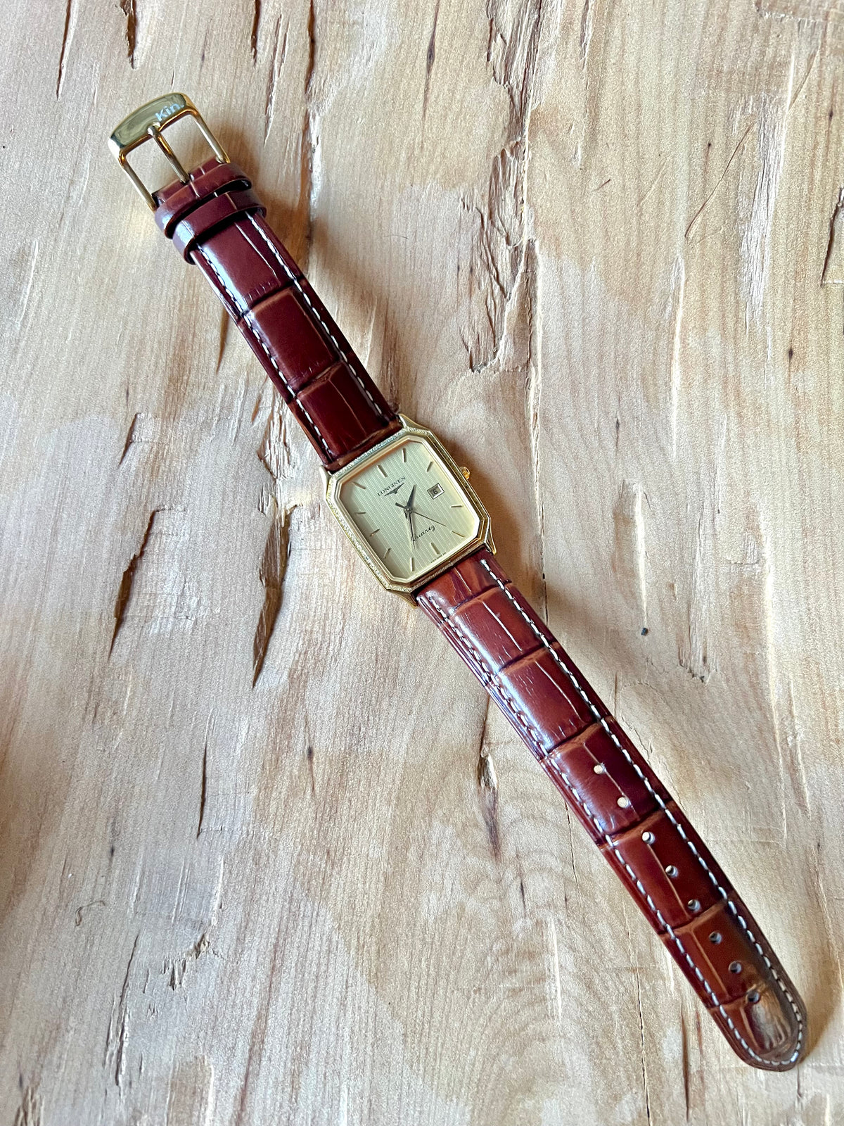 Longines Champagne Textured Bezel Women’s Watch — Full watch laid vertically on a wooden surface