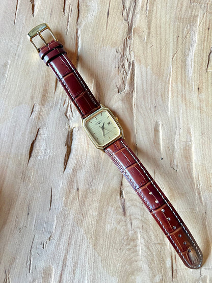 Longines Champagne Textured Bezel Women’s Watch — Full watch laid vertically on a wooden surface