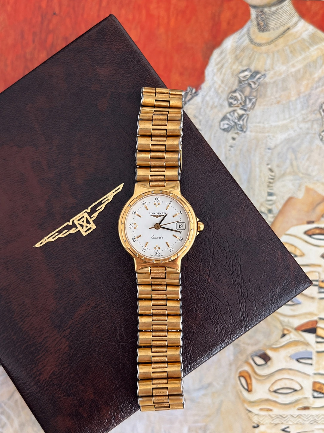 Longines Conquest women's watch with a white dial, gold tone round case and gold bracelet displayed on a Longines box.