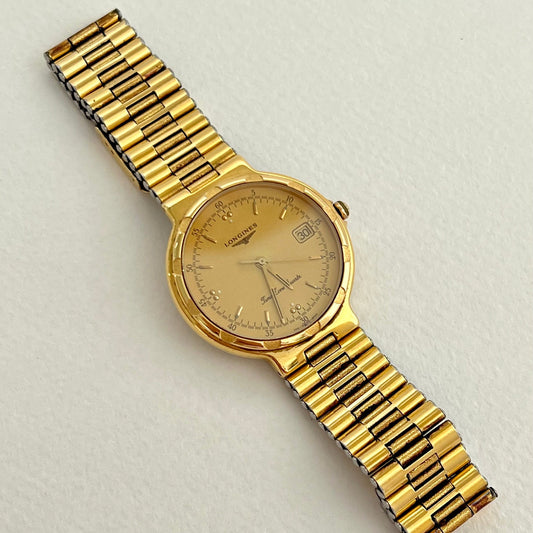 Longines Conquest large gold-tone ladies watch shown on a wrist.