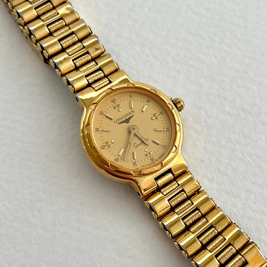 Longines Conquest mini gold-tone ladies watch shown on a wrist.