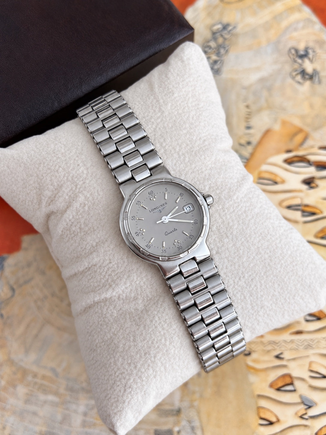 Angled Longines Conquest silver grey dial watch showing textured bezel accents and integrated silver tone bracelet.