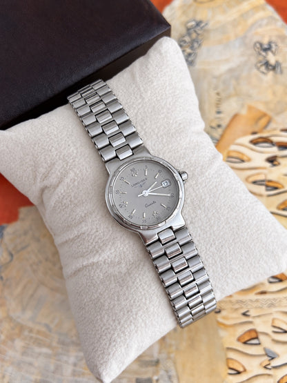 Angled Longines Conquest silver grey dial watch showing textured bezel accents and integrated silver tone bracelet.