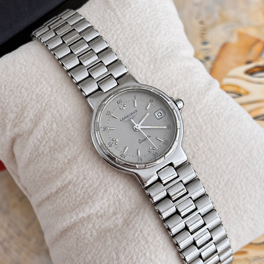 Close view of the Longines Conquest silver grey dial, silver baton markers, grouped dots, minute numerals and date window at three.