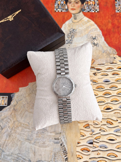 Longines Conquest women's watch with silver grey dial, round silver tone case and integrated bracelet on a cushion beside a Longines box.