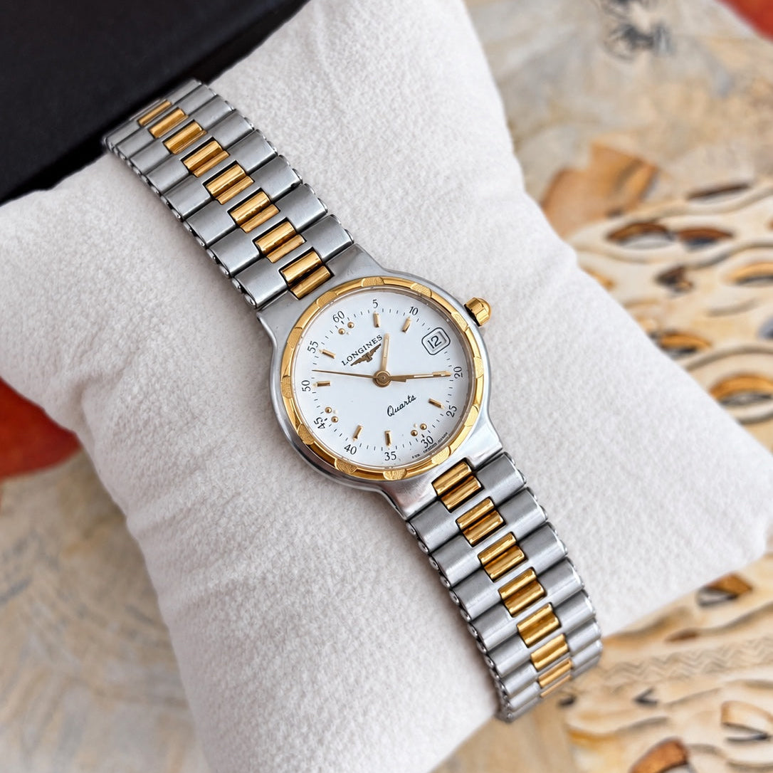 Longines Conquest women's bracelet watch with a white dial, minute numerals, grouped gold tone dots and textured gold tone bezel accents.