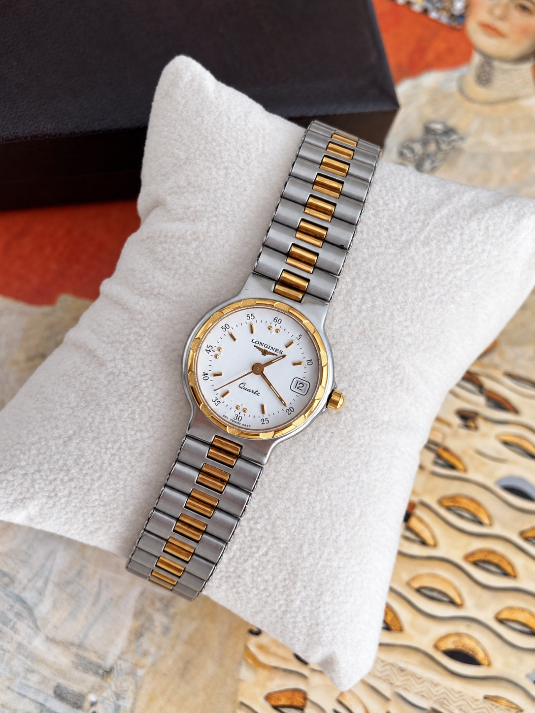 Angled view of the Longines Conquest white dial, gold tone hands and hour markers, framed date window and two tone bracelet.