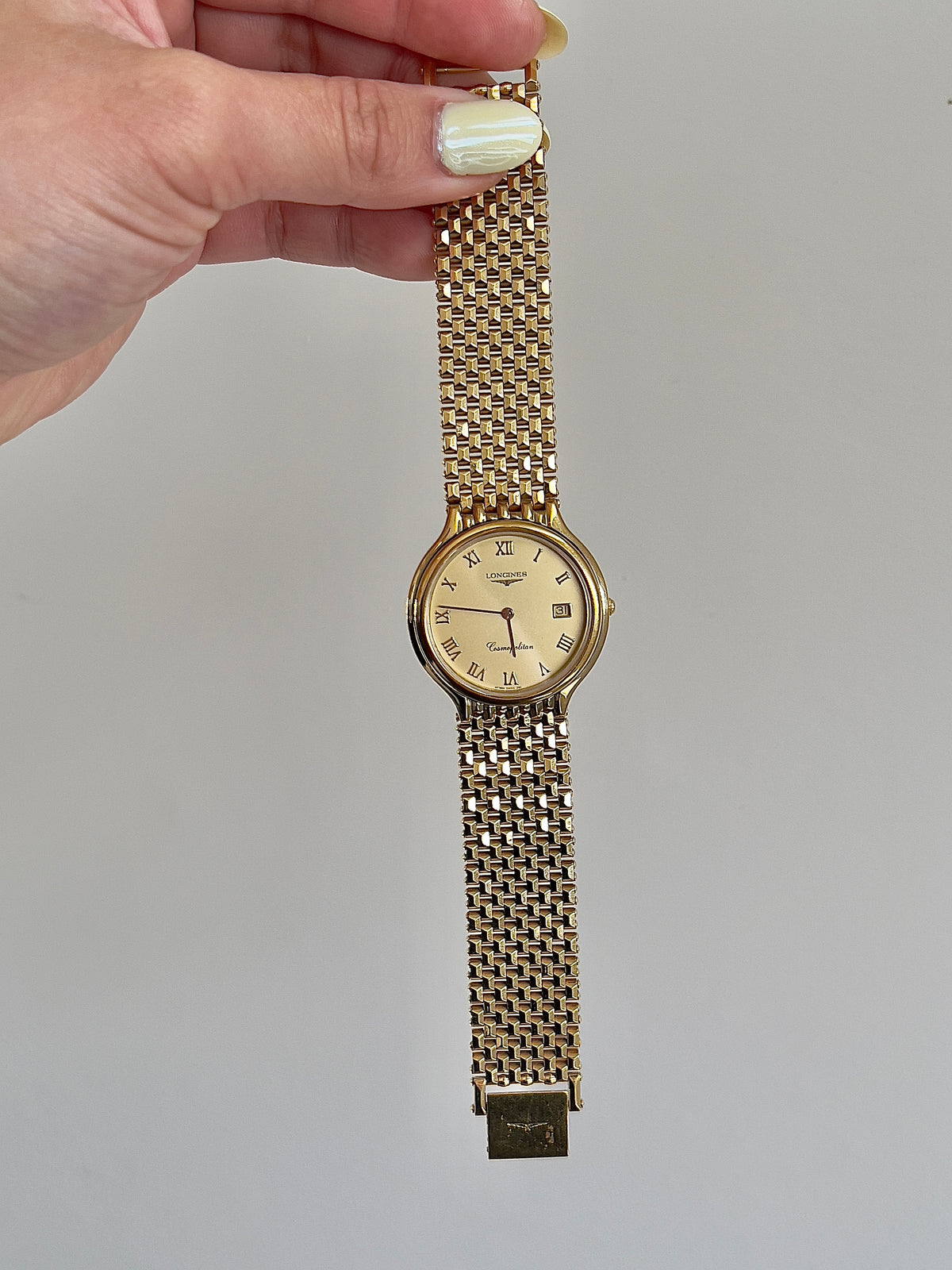 Longines Cosmopolitan Gold Roman Dial Unisex Watch — watch held by bracelet.