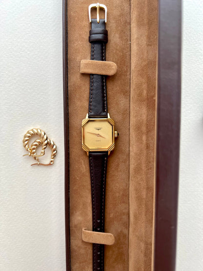 Angled view showing the stepped Deco-style gold corners and cabochon crown on the Longines watch.