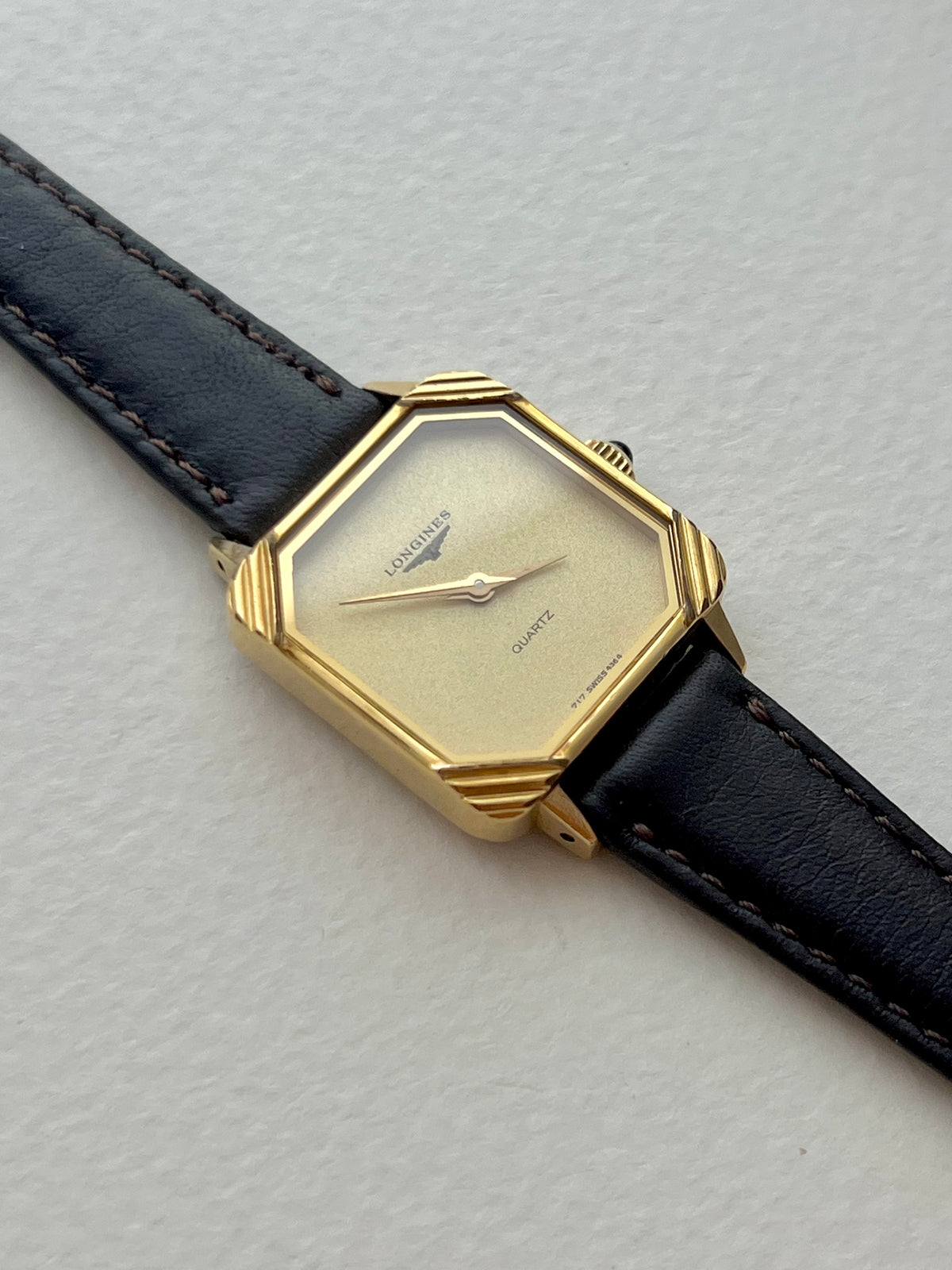 Full front view of the Longines square champagne-dial watch with black leather strap and ornate gold corners.