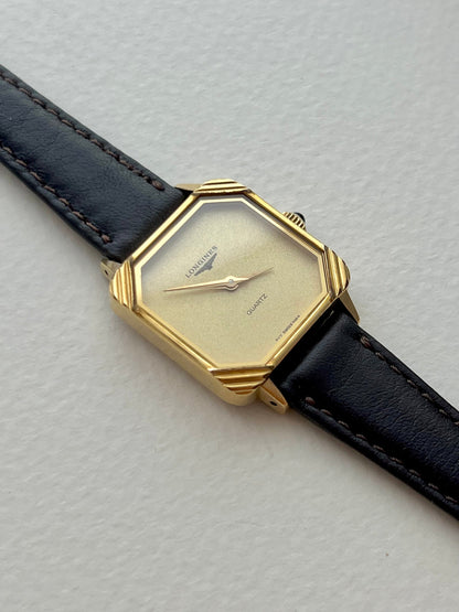 Full front view of the Longines square champagne-dial watch with black leather strap and ornate gold corners.