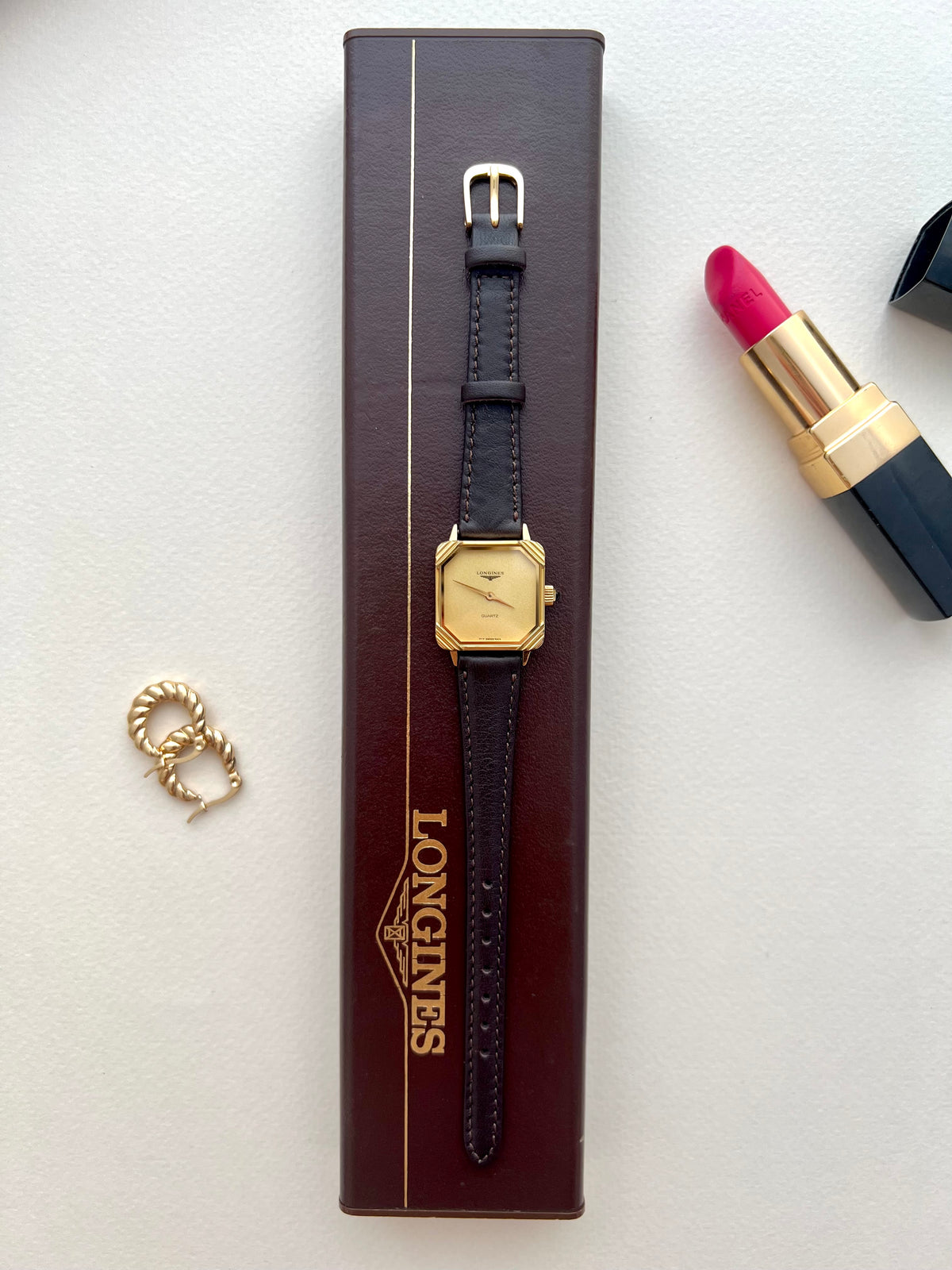 Longines square gold-tone ladies watch with black strap shown on the wrist.