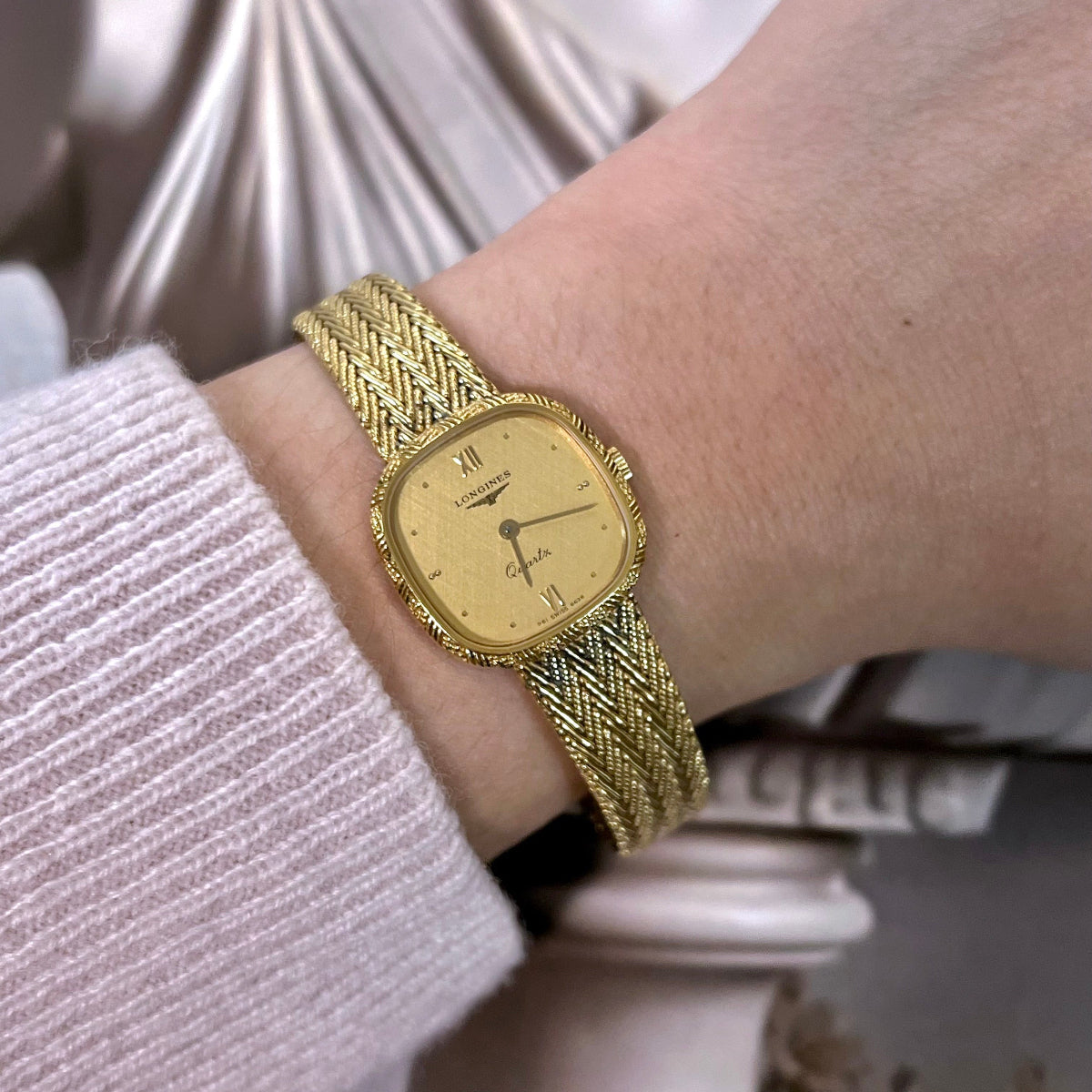 Longines women’s watch with braided gold tone bracelet, champagne dial, Roman numeral accents and rope detailed bezel.